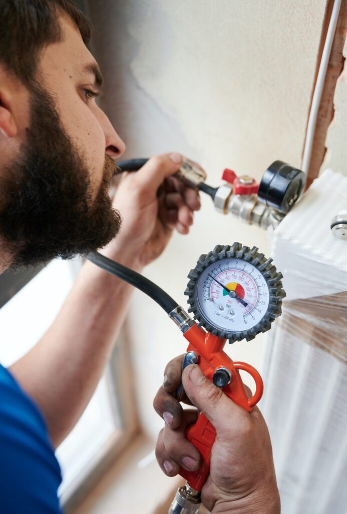 Male plumber checking gas tightness of heating system.